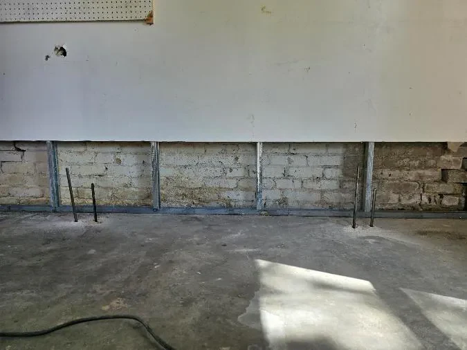 Injection probes standing in the slab along the brick foundation wall of a 1950s Denver basement