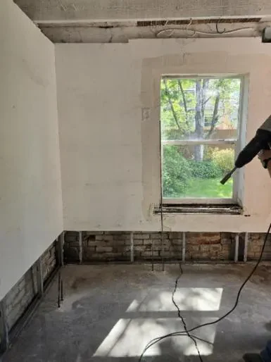 The same Denver basement during injection, with a crack running across the slab toward the settled foundation wall