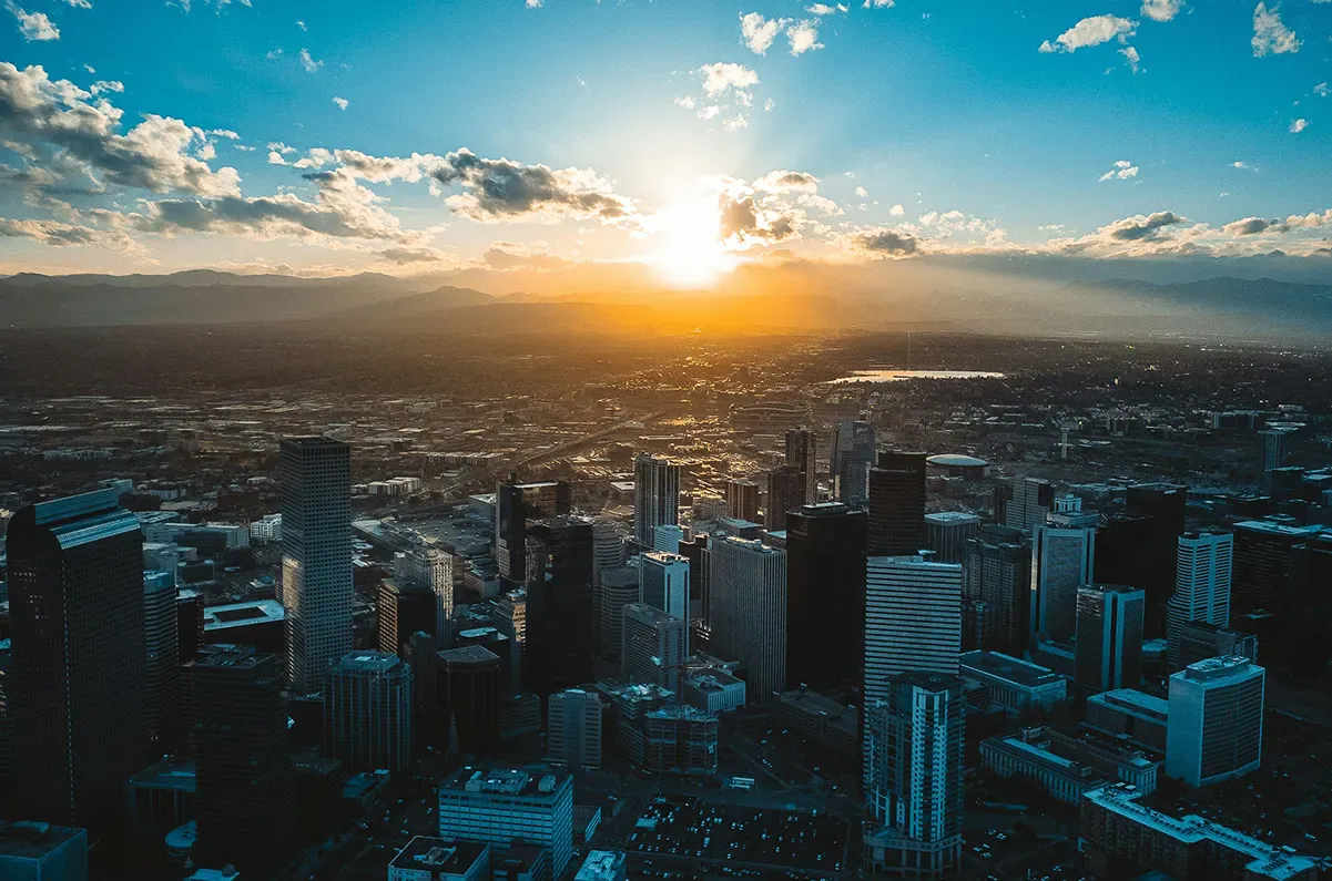 Downtown Denver at sunset, with the sun going down behind the Front Range